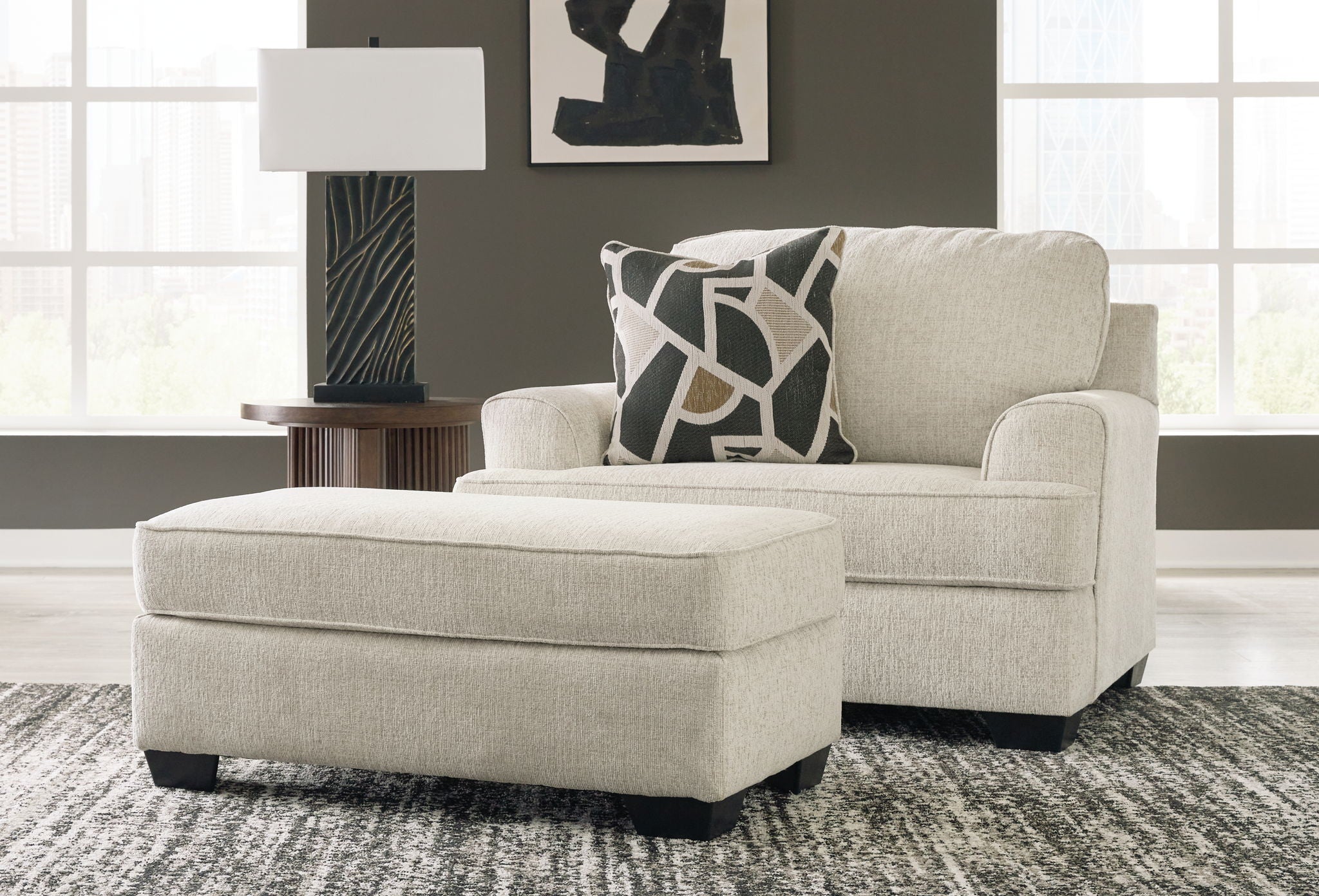 Beige upholstered loveseat with patterned throw pillows and matching ottoman