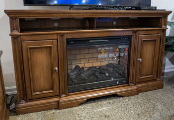 Brown wooden TV stand with fireplace insert and glass front