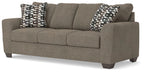 Gray suede sofa with three seat sections and two patterned throw pillows