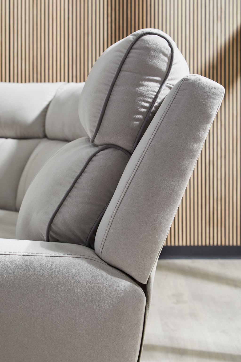 Light gray reclining seat with padded headrest and stitched pillow edge