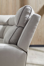 Light gray reclining seat with padded headrest and stitched pillow edge
