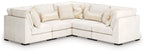 Vanilla sectional sofa with rounded arms, corner chaise, and quilted back pillows