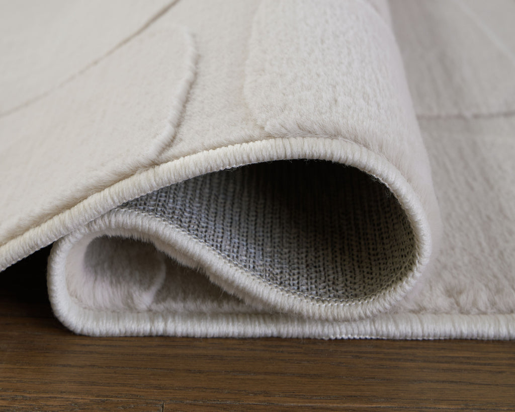 Washable beige rug with rolled edge showing textured woven border