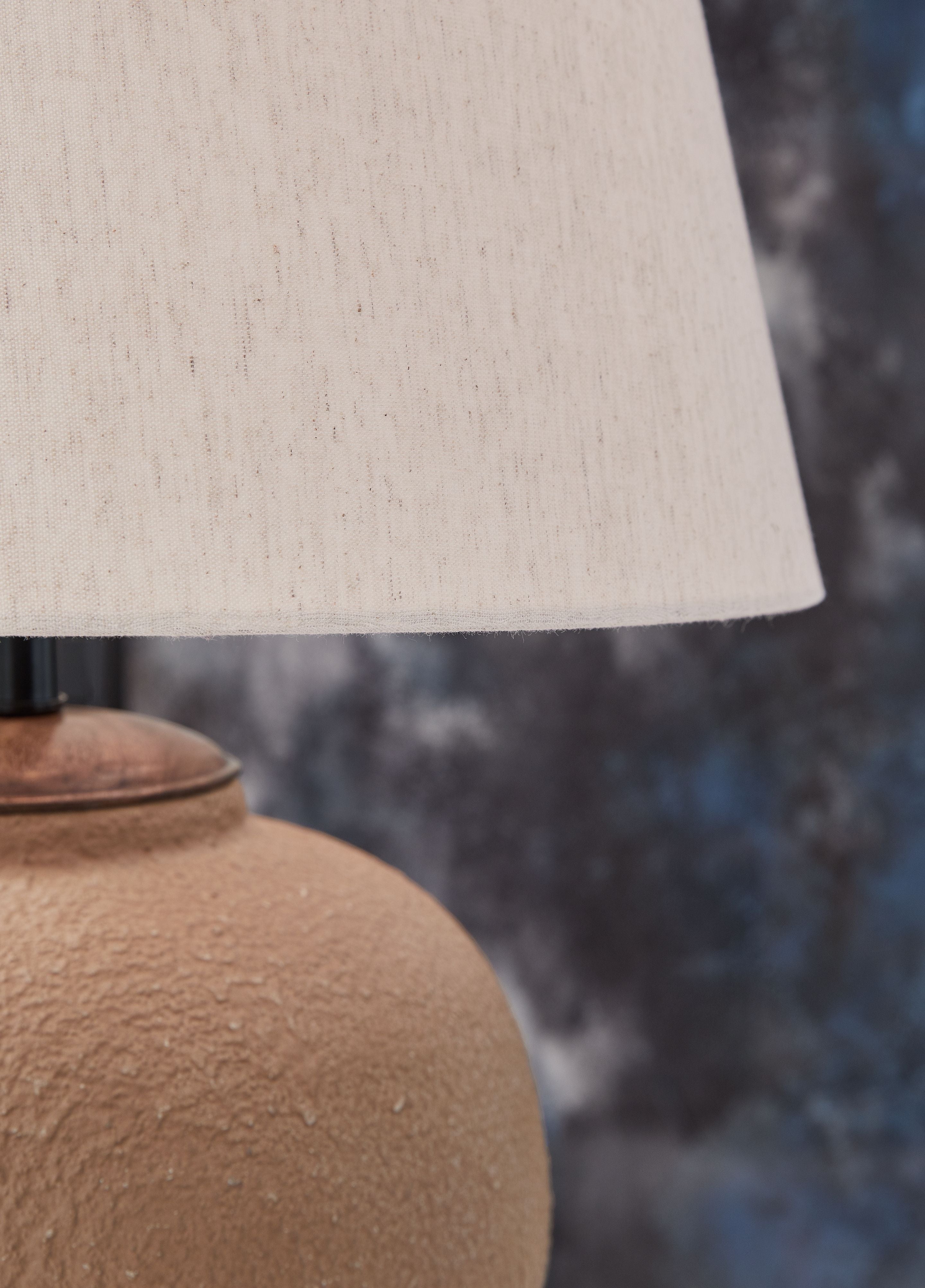 Metal table lamp close-up: rust textured body and off-white fabric shade