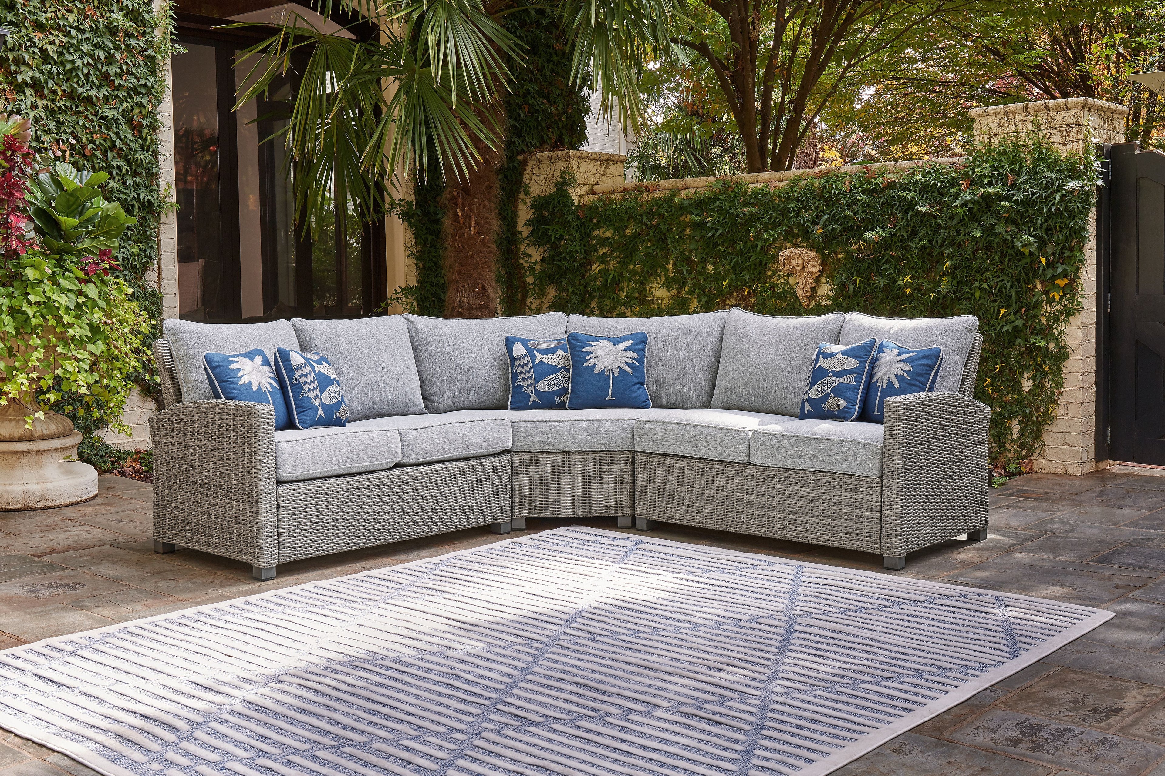 Light gray corner sectional sofa with blue palm and fish patterned pillows