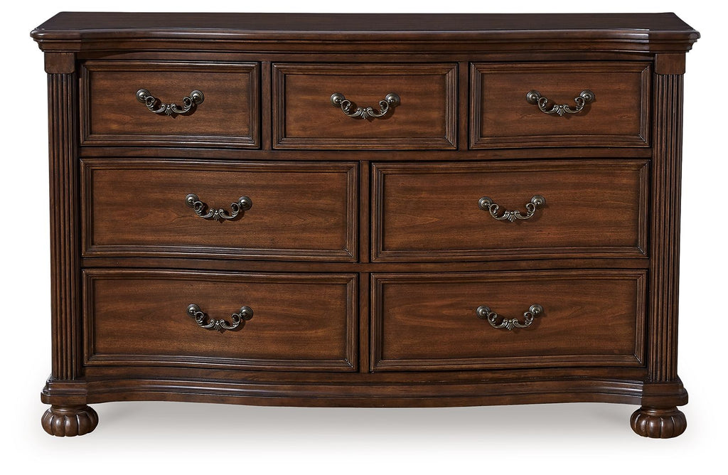 Brown wooden dresser with six drawers and arched metal pulls, thick legs and apron