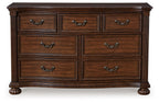 Brown wooden dresser with six drawers and arched metal pulls, thick legs and apron