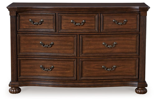 Brown wooden dresser with six drawers and arched metal pulls, thick legs and apron