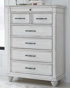 White chest of drawers with six drawers and dark metal bar pulls, carved trim.