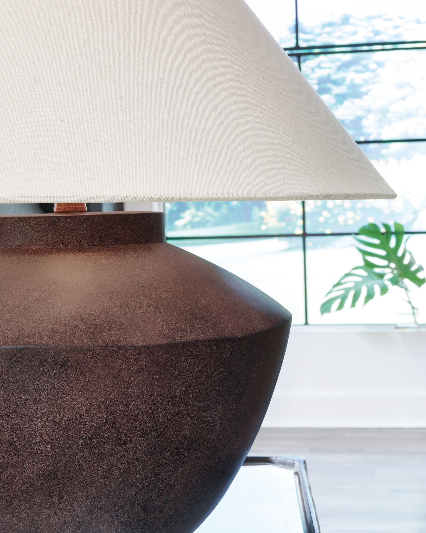 Antique brown table lamp from side, beige shade over textured round base