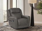 Dark gray power lift recliner with padded arms and sleek seat, shown in a living room