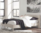 Light wood panel platform bed with white bedding and dark throw