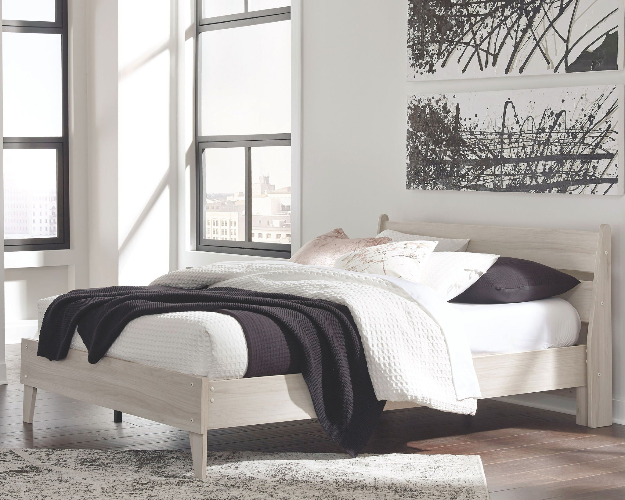 Light wood panel platform bed with white bedding and dark throw