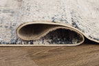 Cream area rug with blue-gray distressed pattern; rolled edge shows low profile.