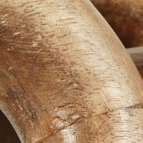Close-up of light brown chain link sculpture with visible wood grain
