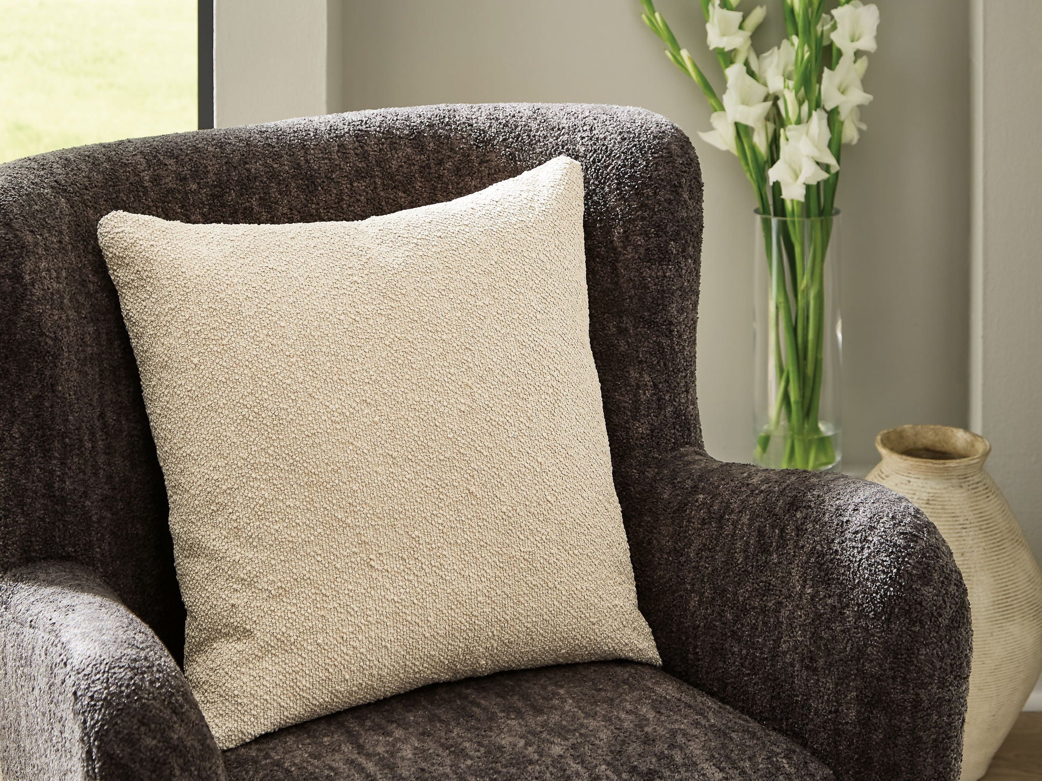 Beige square throw pillow on dark armchair