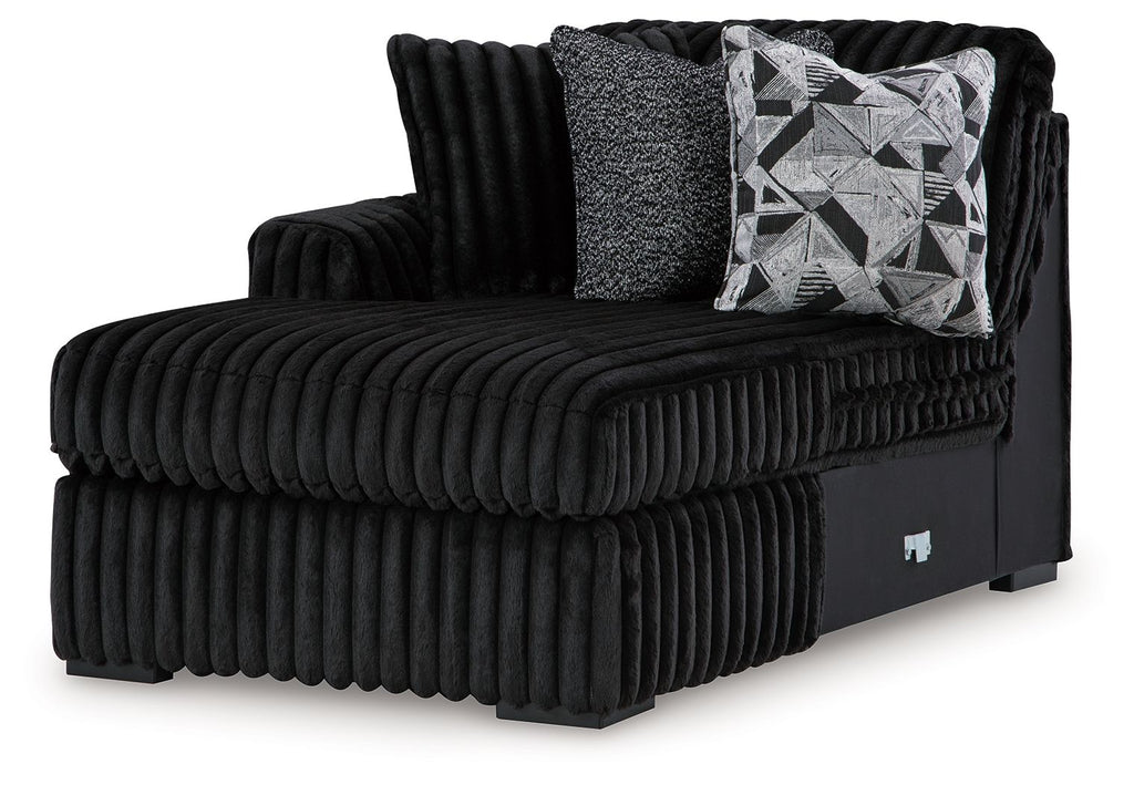 Onyx corner chaise with ribbed plush upholstery, dark frame, and patterned back pillows
