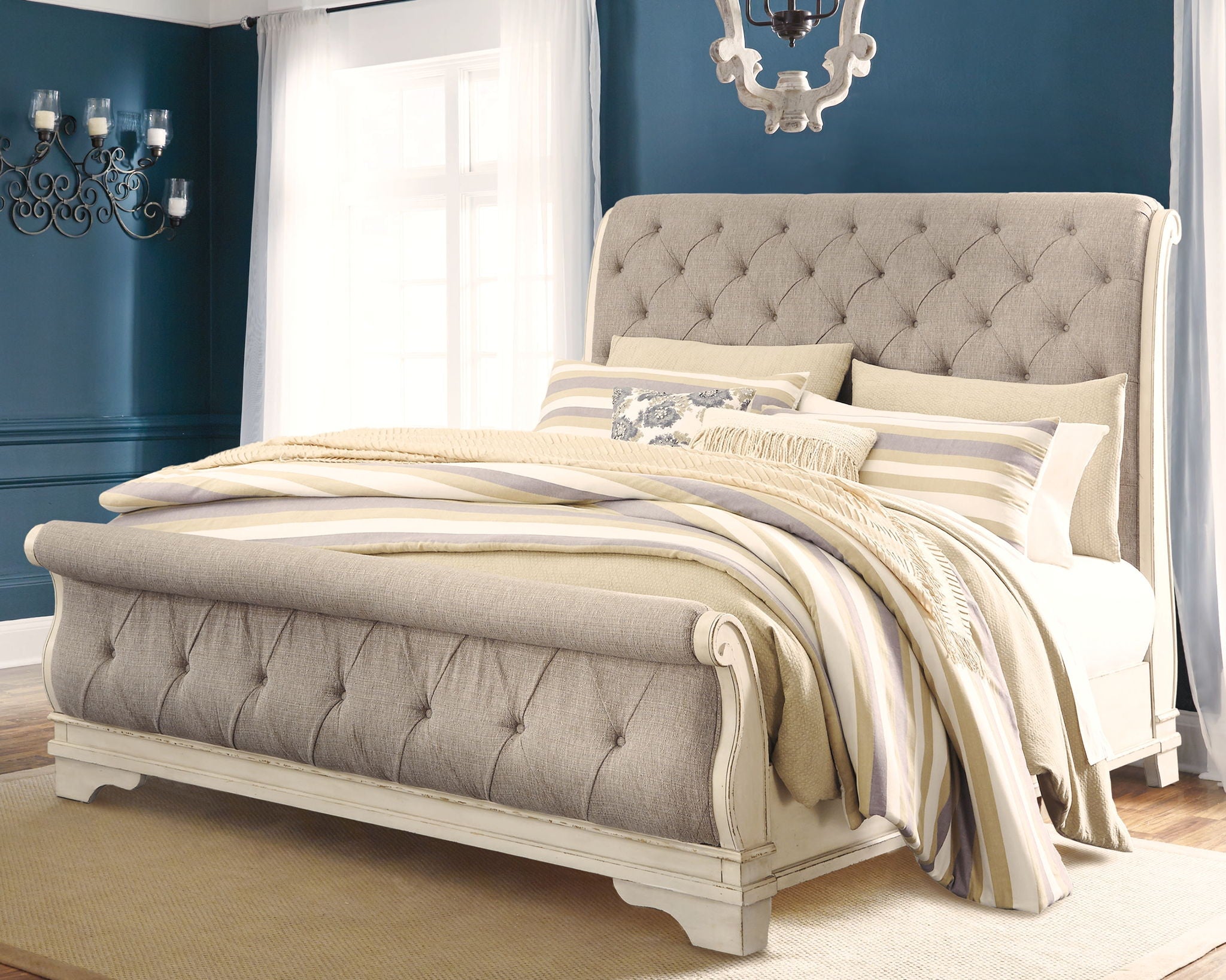 Gray upholstered sleigh bed with tufted headboard and curved side rails, bedding set