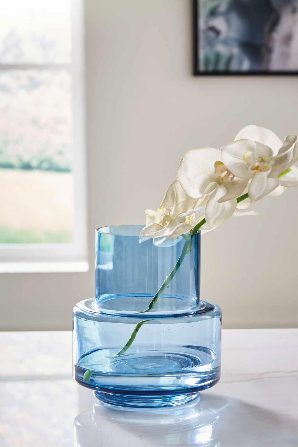 Bealen blue glass vase holding white orchid blooms with green stems