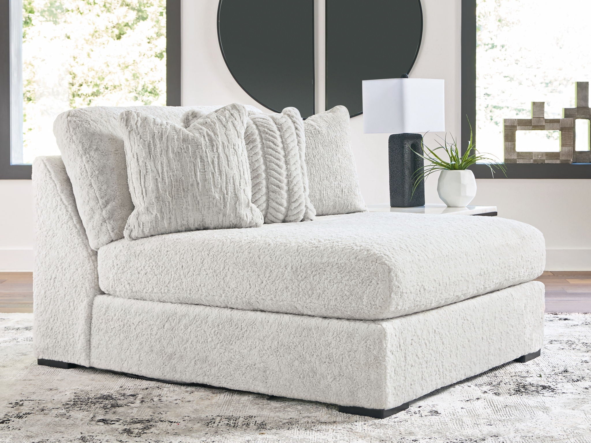 Oversized armless chaise in light gray textured fabric with two throw pillows