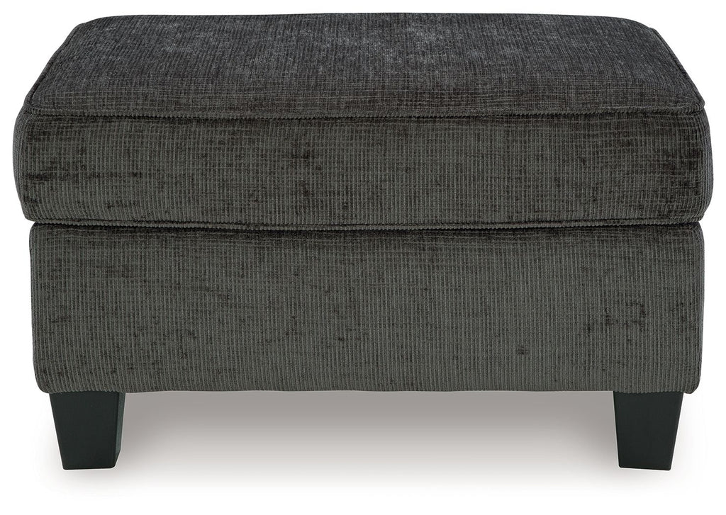 Dark gray ottoman with rounded square top and stitched fabric, short block legs