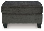 Dark gray ottoman with rounded square top and stitched fabric, short block legs