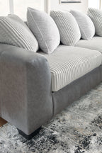 Light gray sectional sofa seat with ribbed cushions and striped throw pillows.