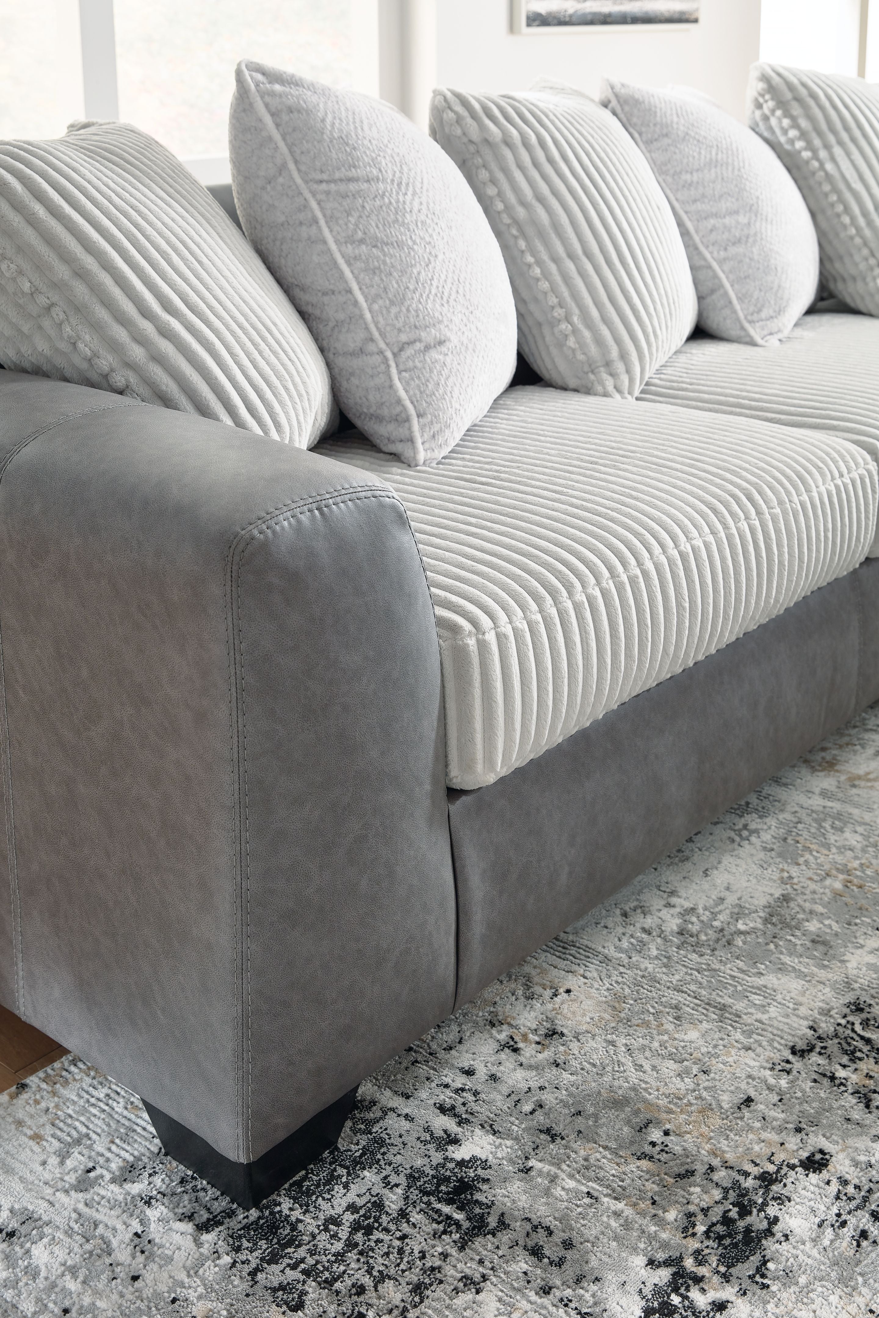 Light gray sectional sofa seat with ribbed cushions and striped throw pillows.