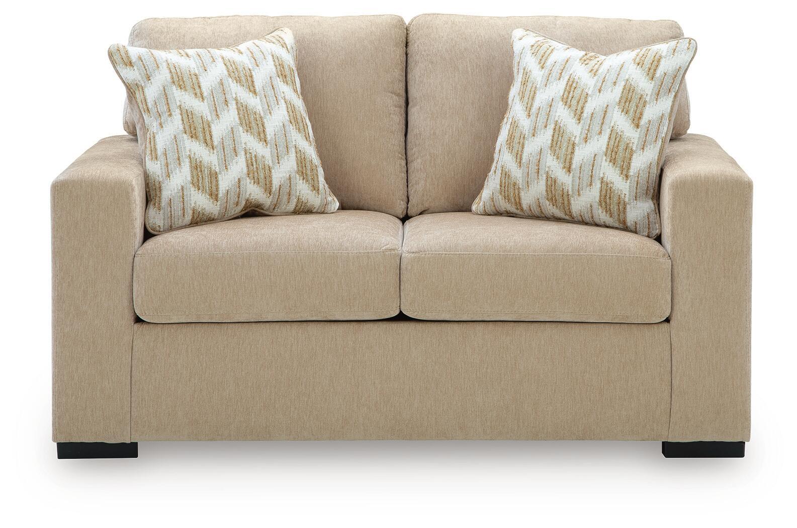 Light tan upholstered loveseat with two geometric throw pillows