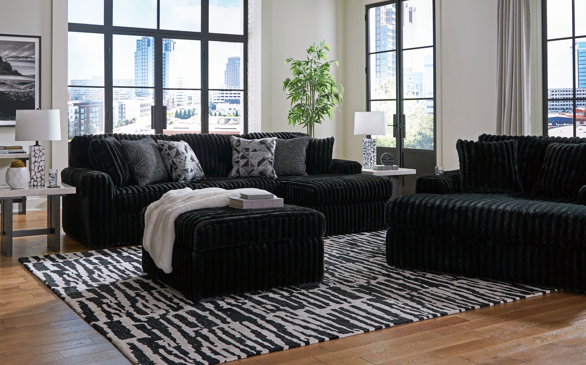 Black sectional sofa with chaise seating and tufted ottoman cube