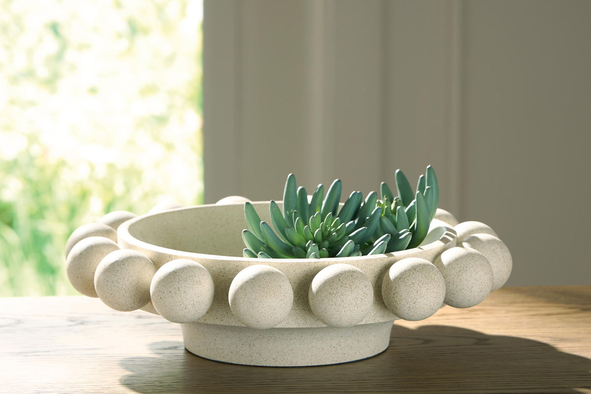 Beige stone-textured bowl planter with pebble rim holding a green succulent