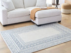 Geometric blue rug with border pattern, displayed in living room