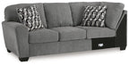 Gray sofa with corner wedge, two patterned throw pillows, and dark base panels
