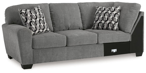 Gray sofa with corner wedge, two patterned throw pillows, and dark base panels