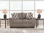Light brown loveseat with two plaid throw pillows