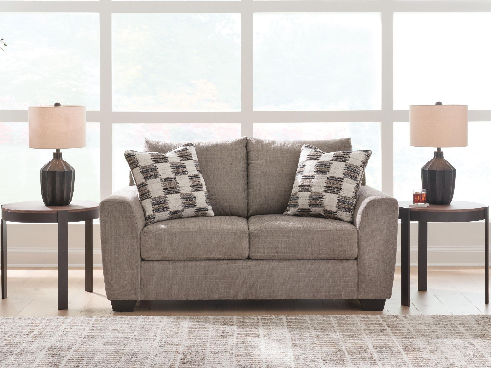 Light brown loveseat with two plaid throw pillows