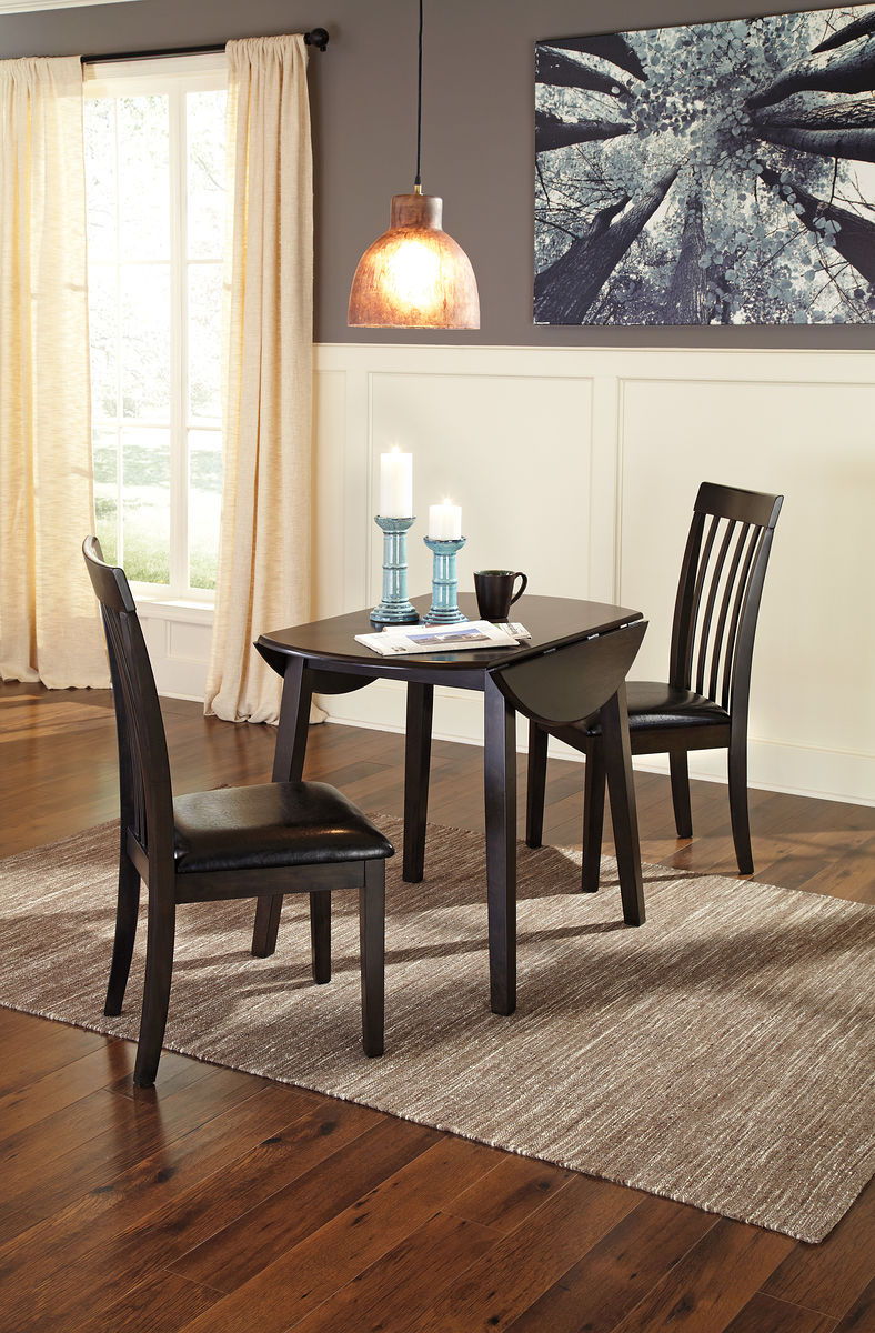 Dark brown round dining table with two slat-back chairs and black seat cushions