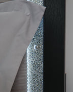 Upholstered headboard edge with glittery inset, silver button, and dark wood trim.