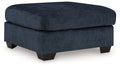 Navy upholstered ottoman with round-corner lid and dark block legs.