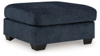 Navy upholstered ottoman with round-corner lid and dark block legs.