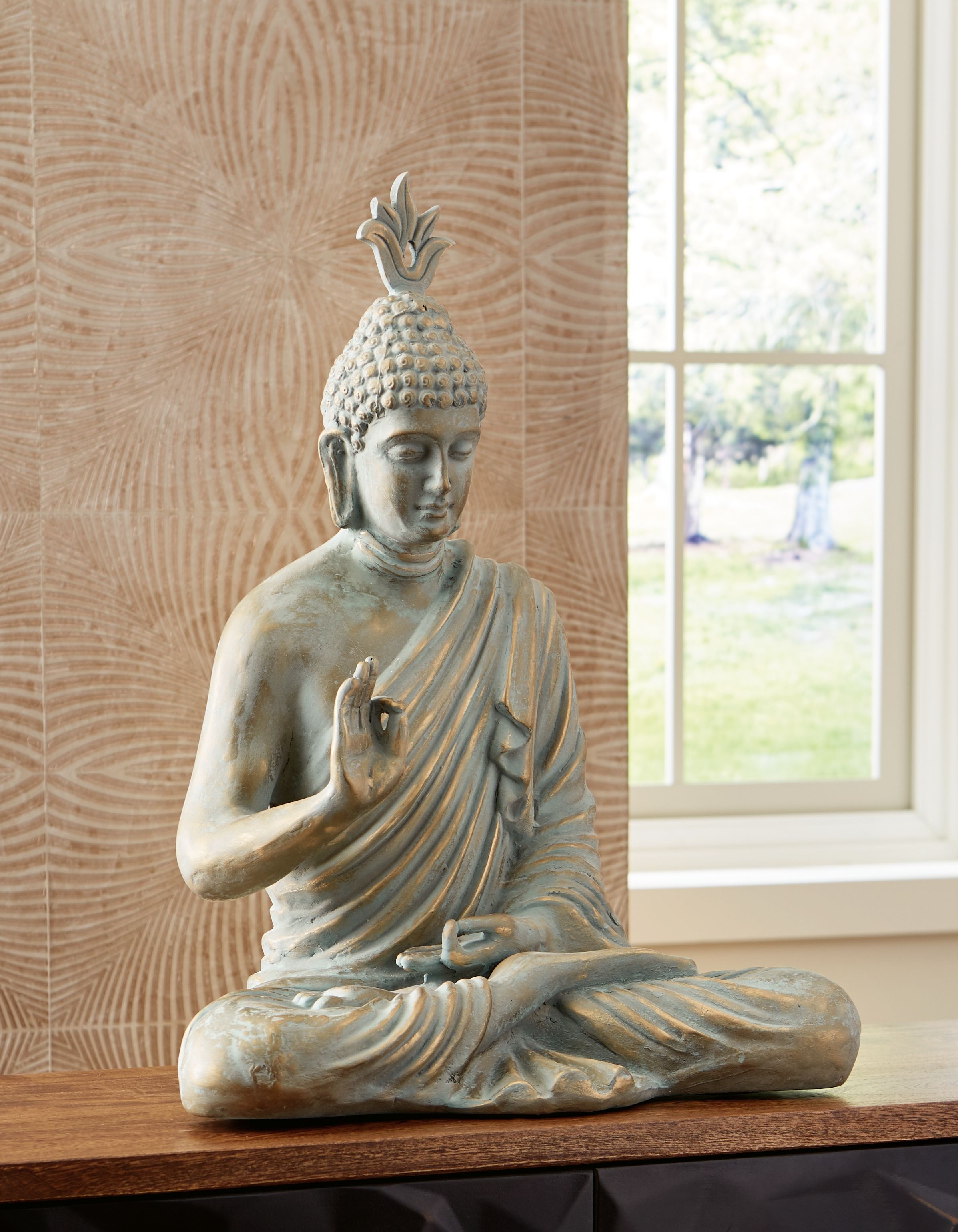 Seated Buddha sculpture with green patina, one hand raised and the other resting