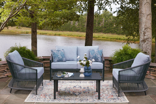 Outdoor loveseat and two armchairs with light gray cushions, blue pillows, and coffee table