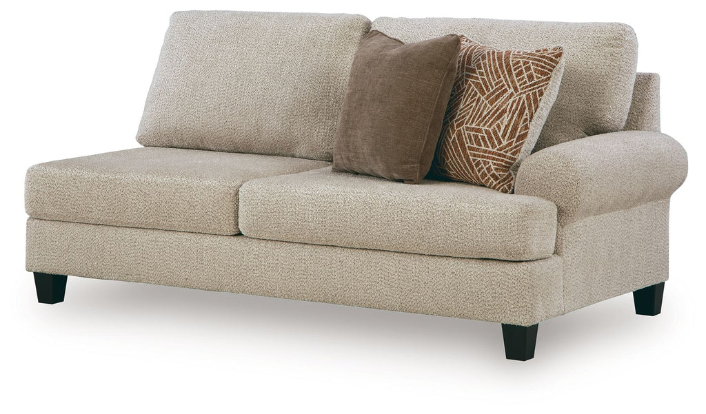 Light beige upholstered sofa with rounded arms, two cushions, and patterned throw pillow