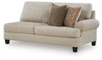 Light beige upholstered sofa with rounded arms, two cushions, and patterned throw pillow