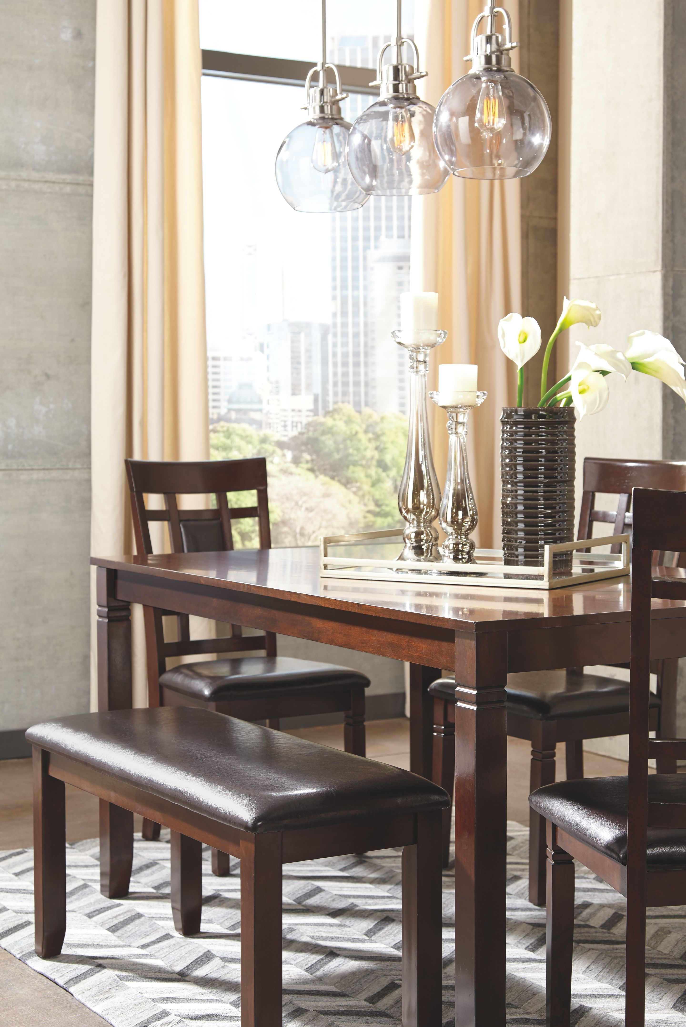 Brown dining table set with glass tabletop, four chairs, and dark cushioned bench