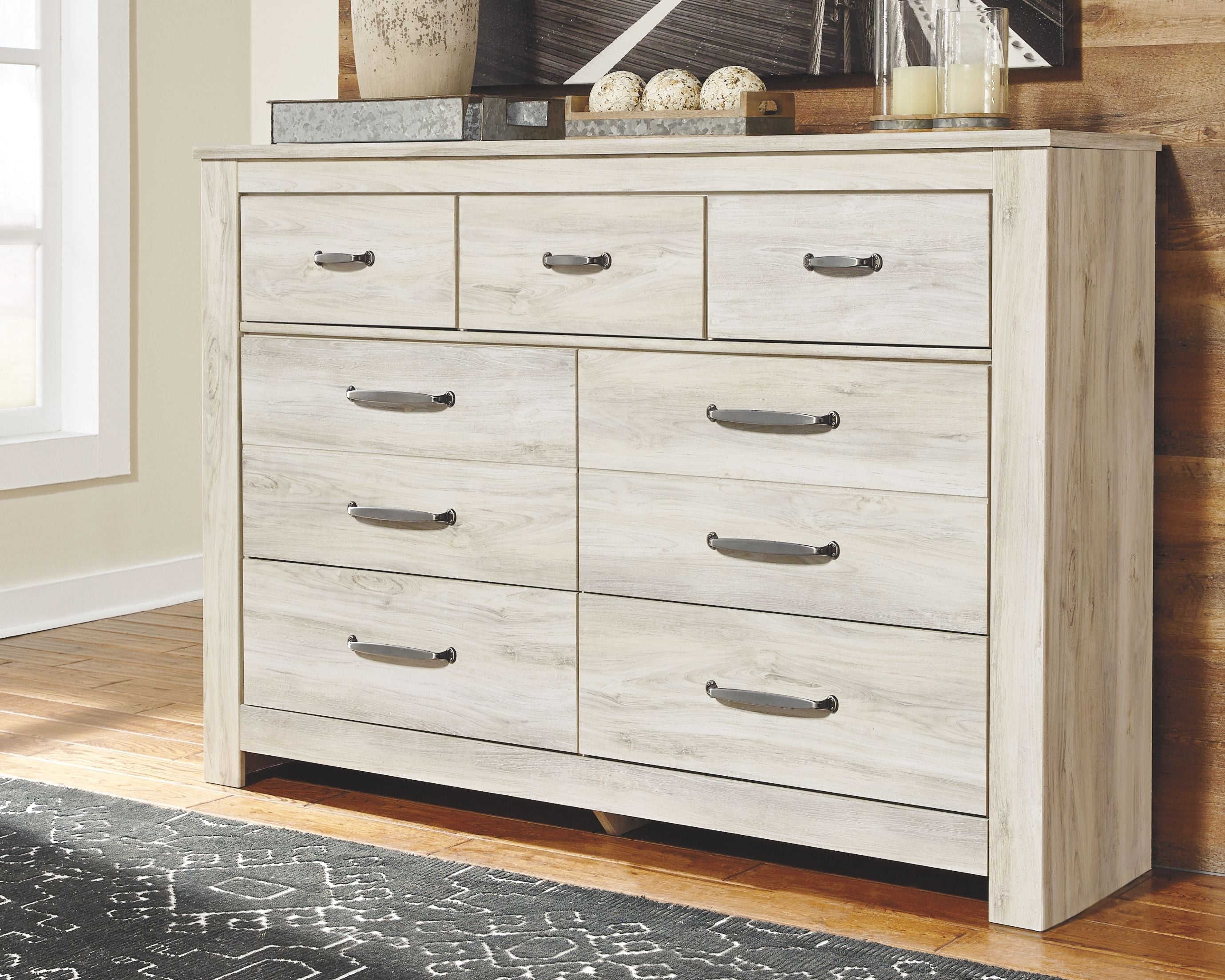 Light brown wooden dresser with multiple drawers and dark metal bar handles