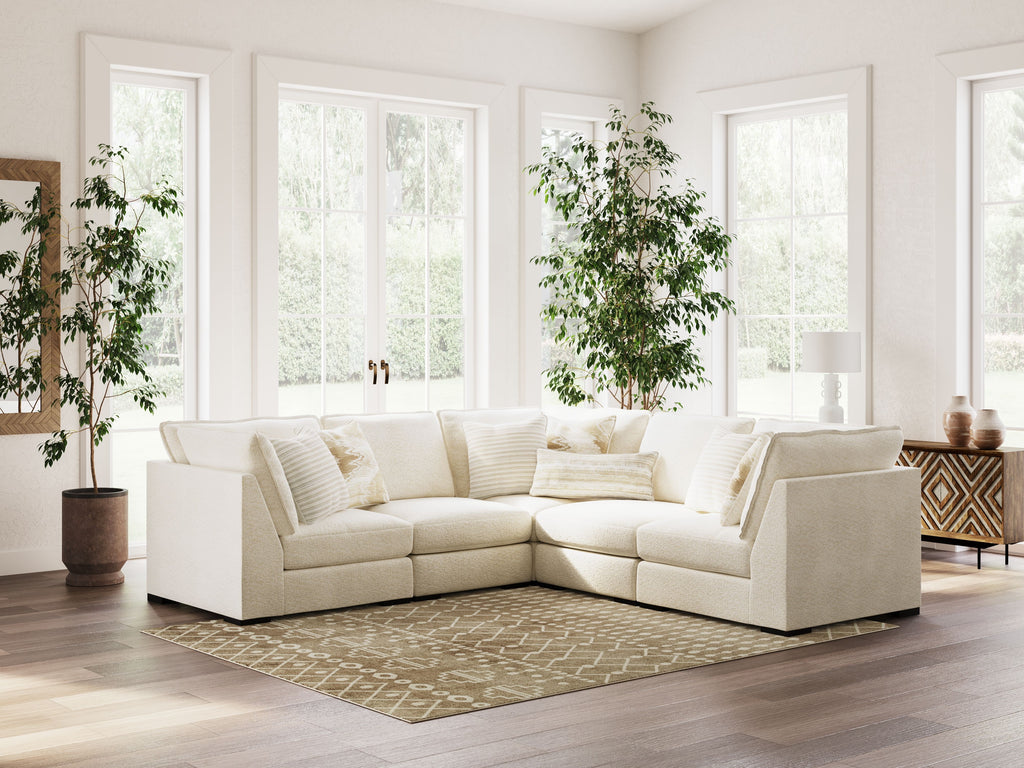 Vanilla sectional sofa with chaise-style corner, layered throw pillows, and upholstered arms
