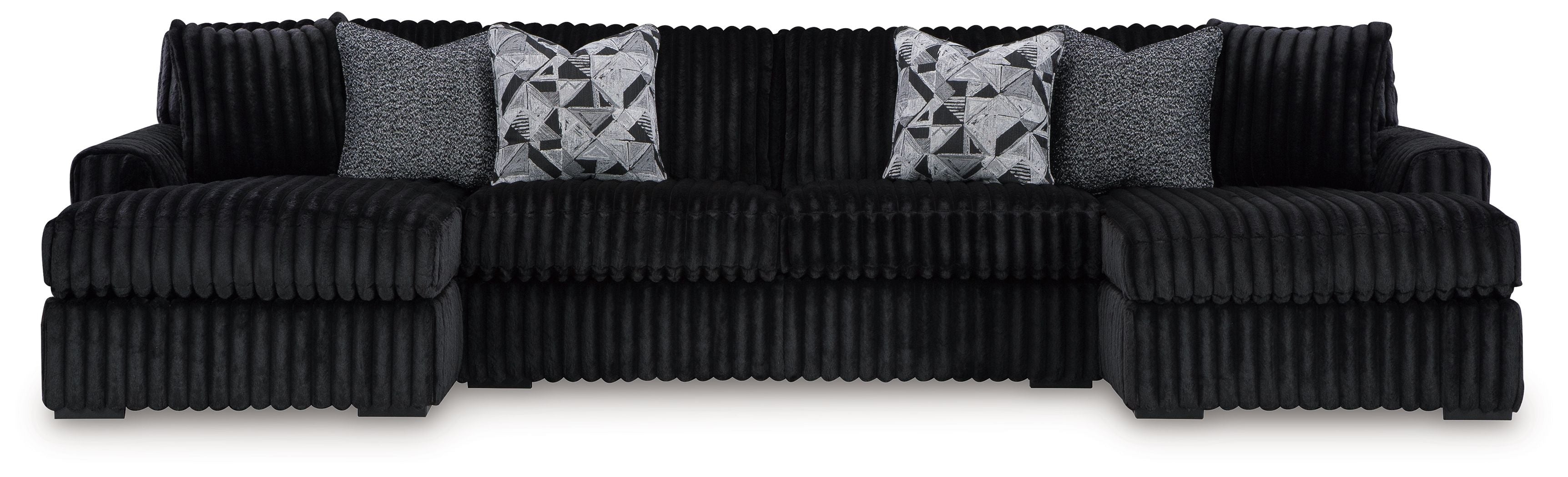 Black sectional sofa with chaise and ribbed arms, featuring four patterned throw pillows