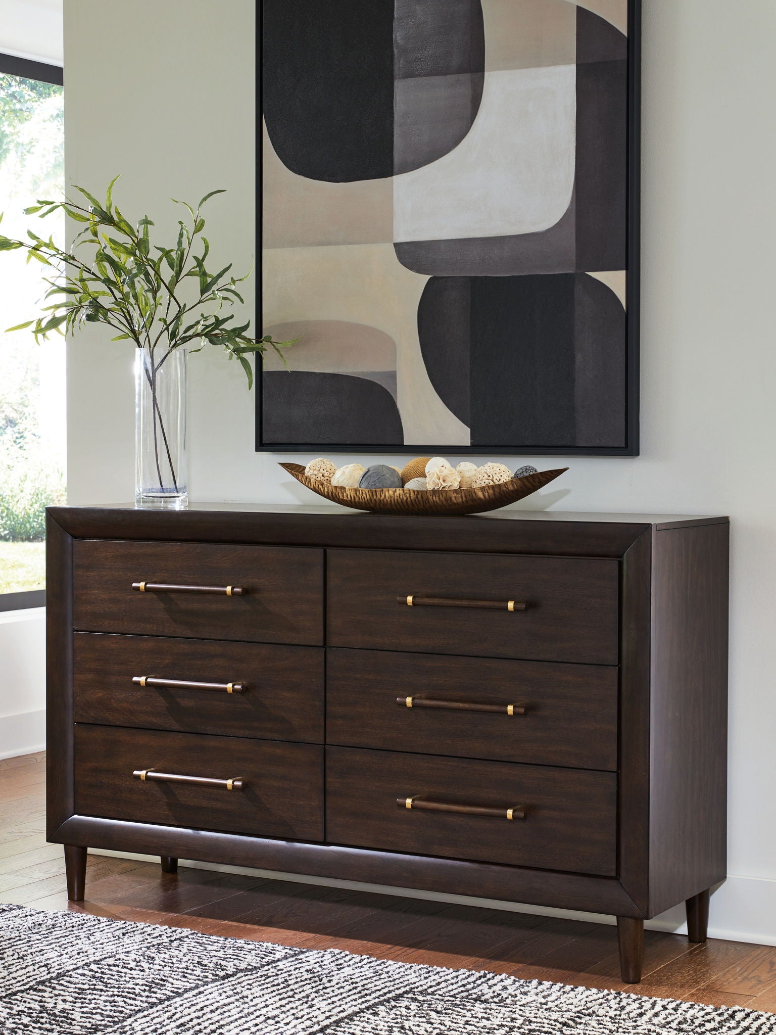Dark brown dresser with six drawers and brass bar pulls, angled view