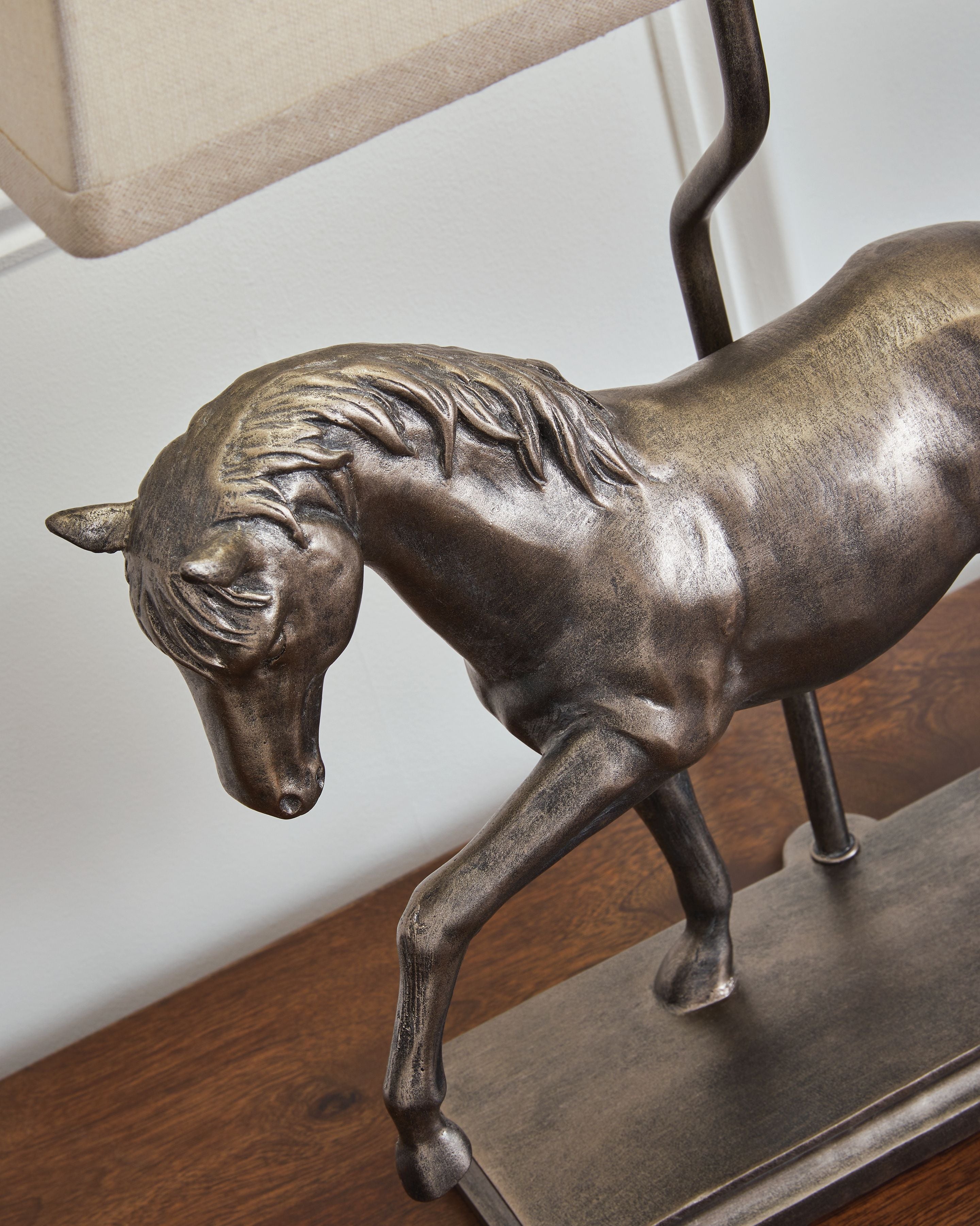 Bronze horse figurine base of table lamp, with part of fabric shade visible.